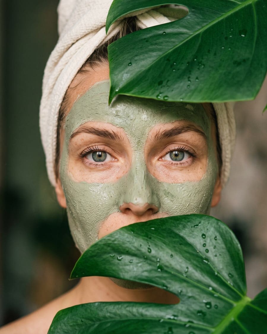Rostro con mascarilla verde entre hojas
